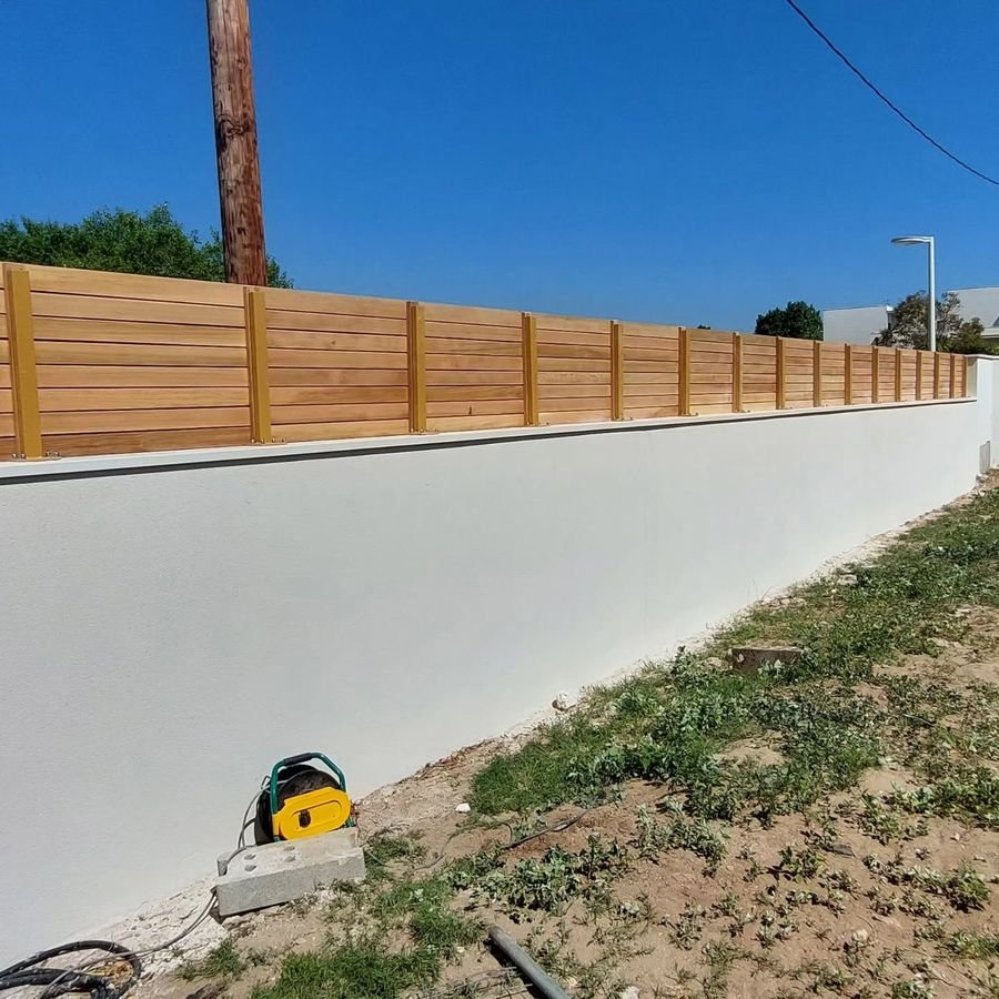 Brise-vue en lames de bois posé sur un mur de clôture