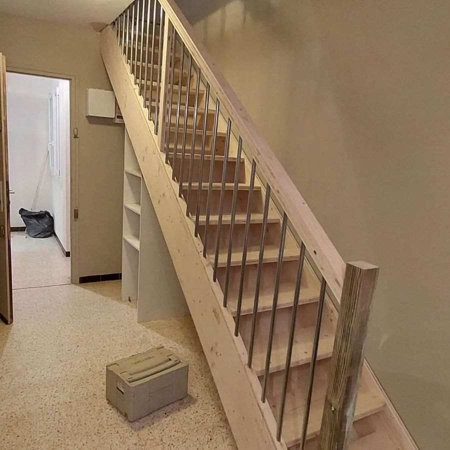 Escalier droit en bois avec garde-corps à barreaux métal et bibliothèque intégrée