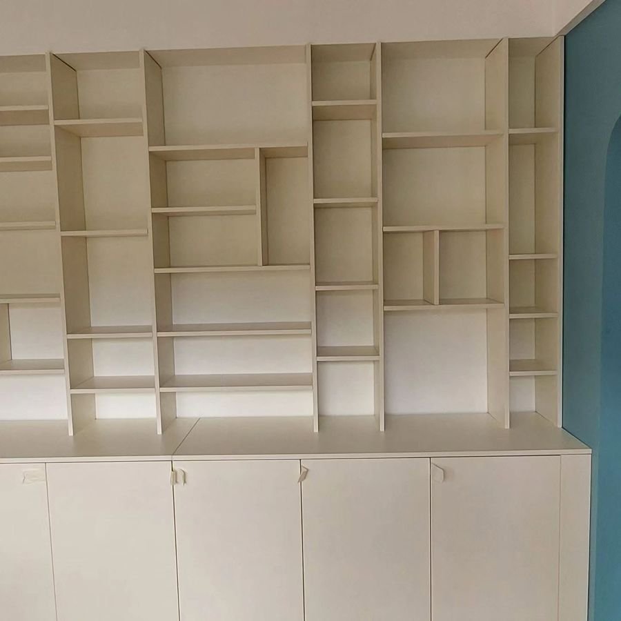 Grande bibliothèque blanche sur mesure avec niches asymétriques et placards bas